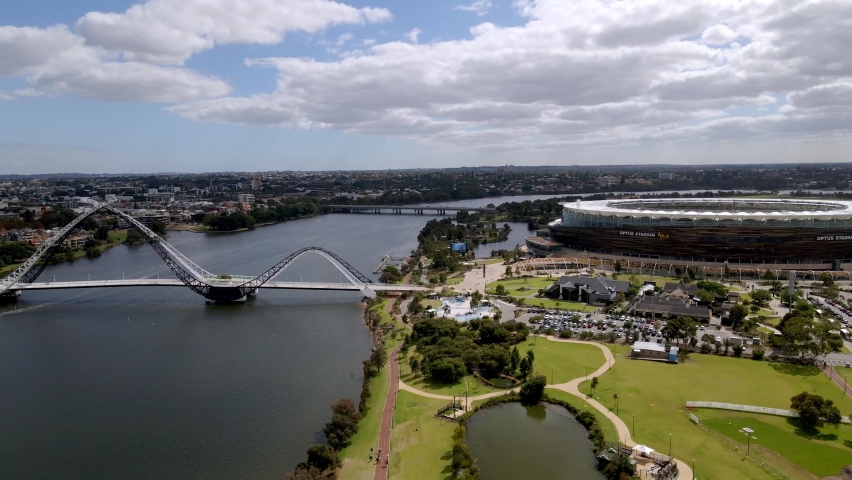 Beautiful bridge over a river, next to Optus stadium and a big green park covered by clouds in Perth, Australia