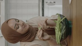 Woman in hijab watching recipe or funny video on tablet computer while preparing food at kitchen table. The woman follows what's going on in the world as she prepares food for herself and her family.