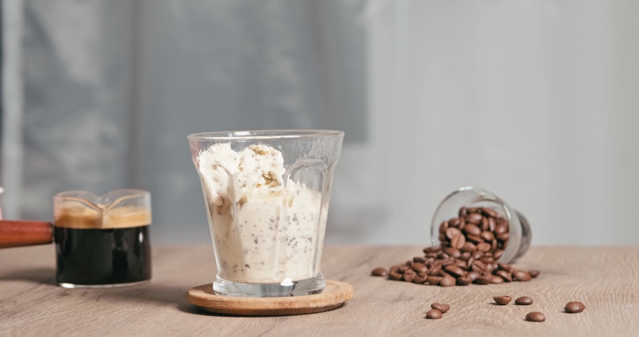 homemade Affogato is Italian dessert with coffee and scoop of gelato or vanilla ice cream into a cup. Then pour one shot of hot espresso. used hand pouring hot black coffee on ice cream in glass Royalty-Free Stock Footage #1093386753
