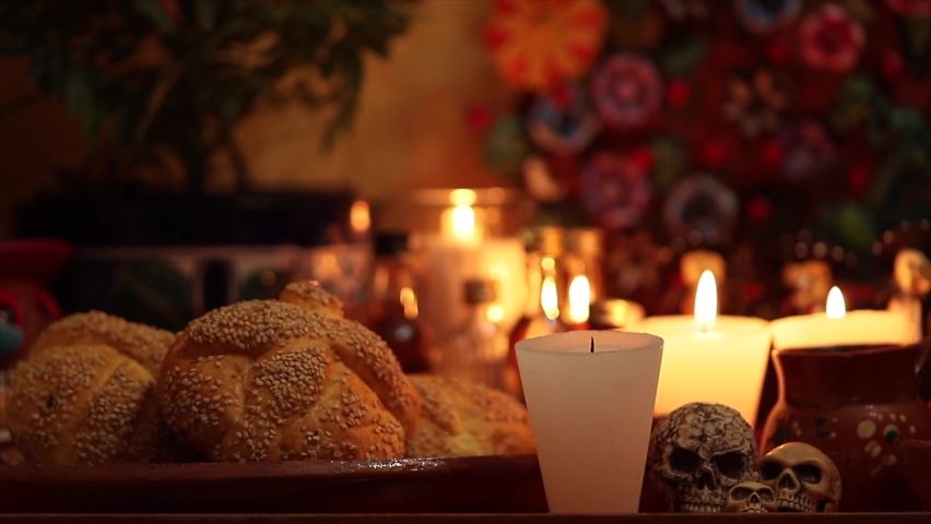 Candle in traditional Mexican altar for Day of the Dead celebration in Mexico with handmade bread and skulls. | Shutterstock HD Video #1093386841