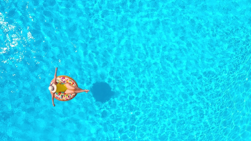 Aerial view of a woman in yellow swimsuit lying on a donut in the pool Royalty-Free Stock Footage #1093389051