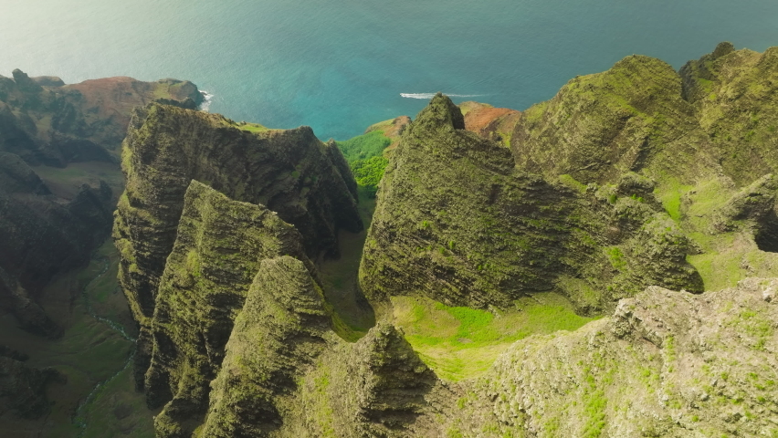Cinematic aerial view of dramatic mountains and ocean on Napali Coast Kauai Hawaii. Aerial view flying over jungle mountain peaks revealing tropical coastline, Na Pali park Kauai. Adventure Royalty-Free Stock Footage #1093389257