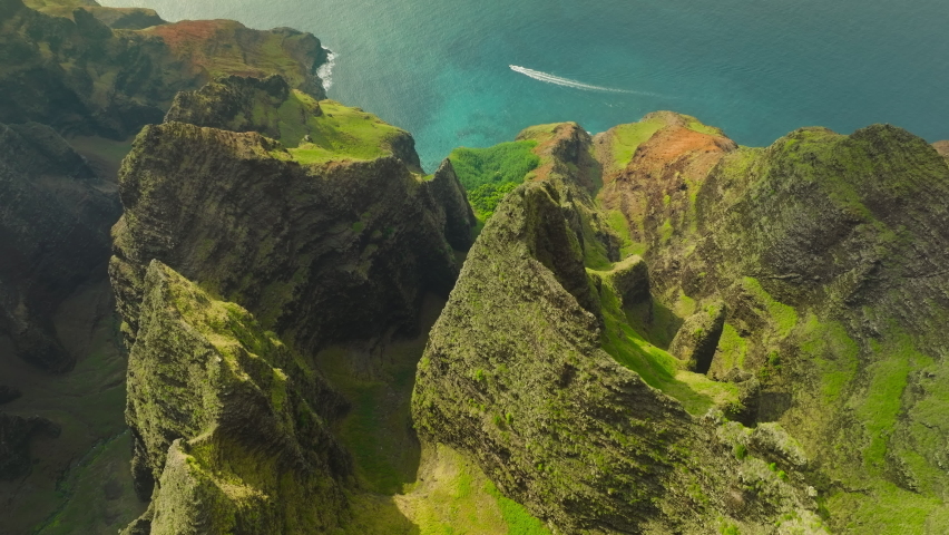 Cinematic aerial view of dramatic mountains and ocean on Napali Coast Kauai Hawaii. Aerial view flying over jungle mountain peaks revealing tropical coastline, Na Pali park Kauai. Adventure