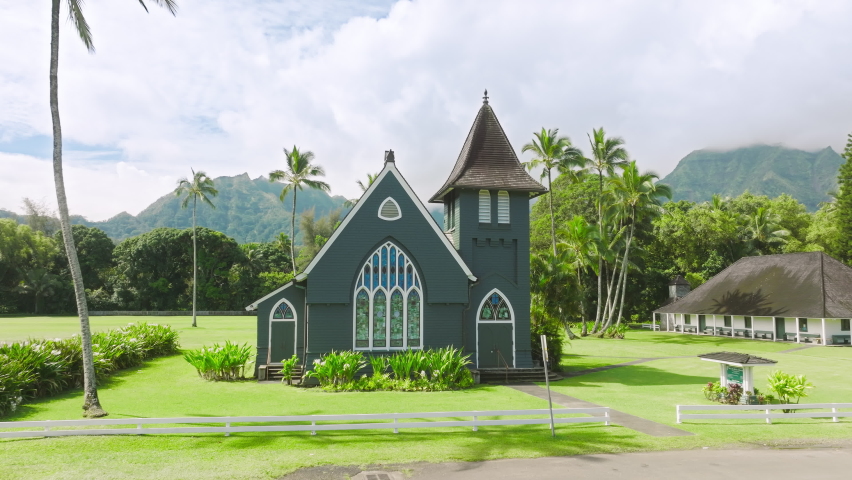 Aerial historic Christian church in American gothic style, drone flying between towers on cinematic nature background. Waioli Huiia Church in Haena on North Shore Kauai island, Hawaii sunny summer