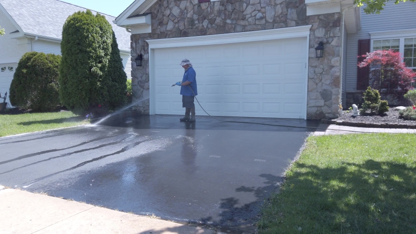 Man wearing boots seen power washing an asphalt driveway Royalty-Free Stock Footage #1093394549