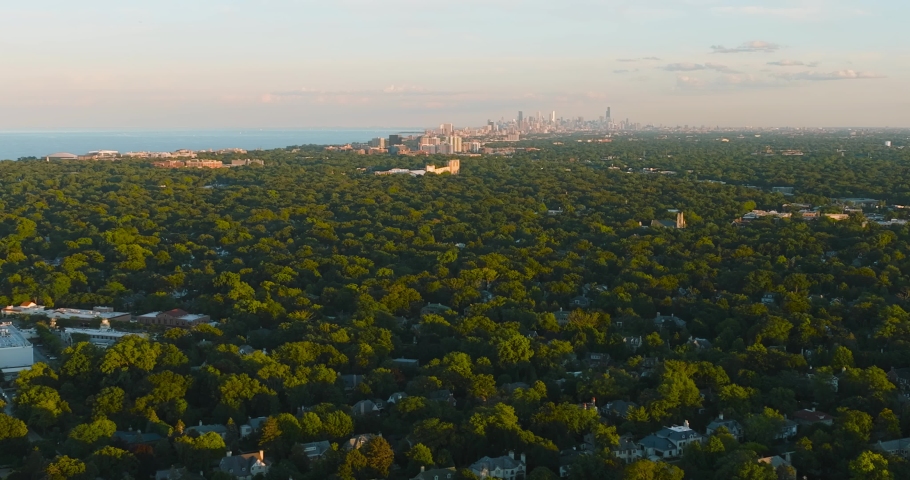Aerial above luxury Chicago North Shore suburbs by the Lake Michigan at sunset. Green areas with trees and parks