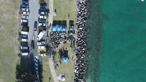 Aerial view looking down at a community event next to a boating channel and harbor. Drone view