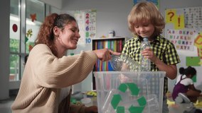 Caucasian female teacher teaching schoolkid about bottle recycle in school playroom. Little boy with teacher put plastic bottle in recycling box. Protect nature lesson  - Powered by Shutterstock - Get 15% off with code: PIKWIZARD15