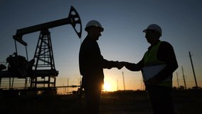 handshake oil contract. handshake a worker and businessman shaking hands against the backdrop of an oil pump. oil sunlight extraction business concept. silhouette handshake business contract - Powered by Shutterstock - Get 15% off with code: PIKWIZARD15