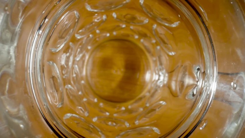 Top view of stream of amber beer pouring into glass. Macro shot of jet of golden drink spilling inside glass, filling it up, forming foam and bubbles. Soda, oil, lager or cider pouring in slow Royalty-Free Stock Footage #1093406047