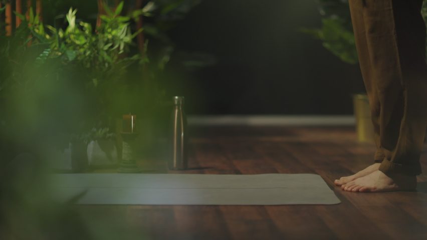 Closeup on middle aged woman with yoga mat folding mat in the green house.
