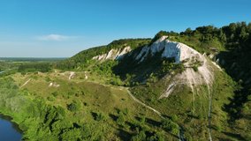Aerial video drone footage. Flight over a white chalk mountain. Green hills, forests and fields. Beautiful landscape.