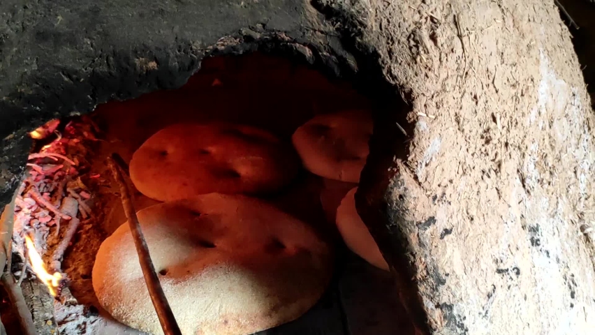 Baking bread in a traditional way in a wood fire oven and flatbread is cooked on the floor. Culture of Moroccan or oriental cuisine by vintage style. Royalty-Free Stock Footage #1093414283