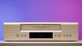 Old video recorder close-up, VHS. Retro player, vintage video cassette broadcasting on purple background, audio tape. 