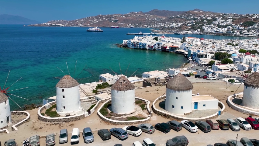 Aerial view through the famous windmills above Mykonos town, Cyclades, Greece, to the Little Venice district during a sunny summer day Royalty-Free Stock Footage #1093417323