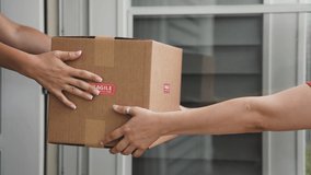 Female Hands of Delivery Driver  Handing Cardboard Box to Customer Close-Up Side View. Slow Motion. Shipping and Delivery Concept - Powered by Shutterstock - Get 15% off with code: PIKWIZARD15