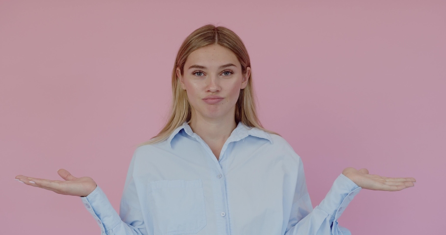 I don't know, who cares. Portrait of confused clueless attractive woman shrugging shoulders, making no idea gesture, whatever. Indoor studio shot isolated on pink background 