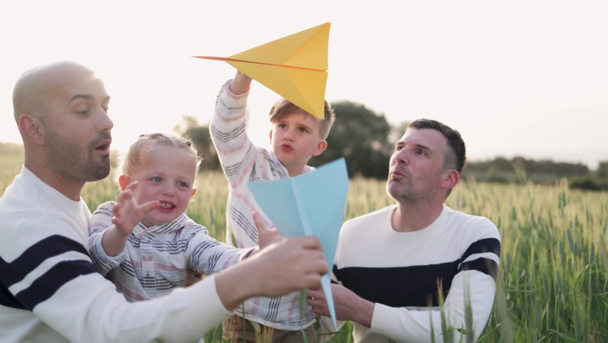 Gay couple of fathers and sons having fun outdoor - LGBTQ family playing with airplane paper toy Royalty-Free Stock Footage #1093423517