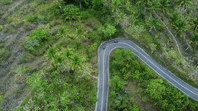 Aerial video of drone following a couple riding motorbikes along scenic road in Nusa Penida, Bali