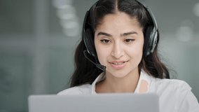 Close-up young woman assistant sales agent advisor hotline consultant answering incoming call using headset looking at laptop screen talking to client giving professional support advertises services
