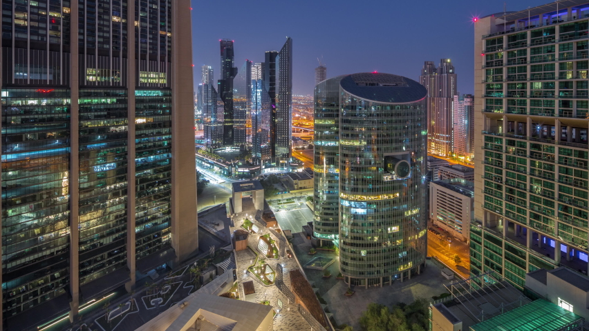 Dubai international financial center skyscrapers aerial night to day transition timelapse. Illuminated towers and walking area on a gate avenue panormic view from above before sunrise Royalty-Free Stock Footage #1093441165