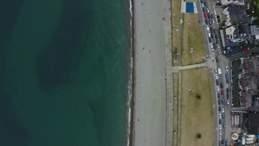 Aerial top-down view of Bray Town with busy streets, parking lots full of cars and many people at the beach. Travel and tourism concept