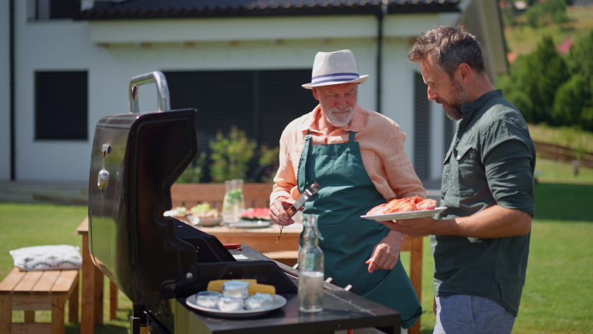 Senior father with adult son grilling outside on backyard in summer family during garden party | Shutterstock HD Video #1093444687