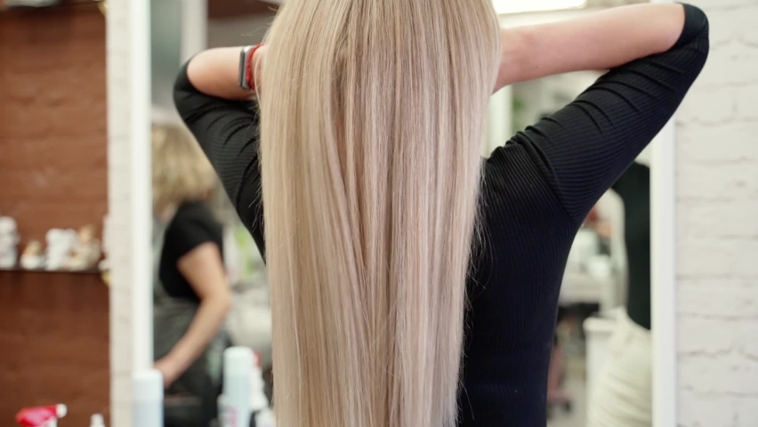 Very long blond hair in a young beautiful woman in a hairdressing salon. beautiful healthy hair. view of beautiful long hair from the back, the hair is beautifully scattered over the arms | Shutterstock HD Video #1093448621
