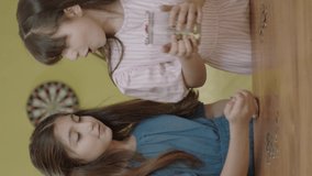 Little girls throw money into the piggy bank, learn to save money, think about the future, learn personal savings. She puts money in the piggy bank at home with his little girlfriend.Vertical video.