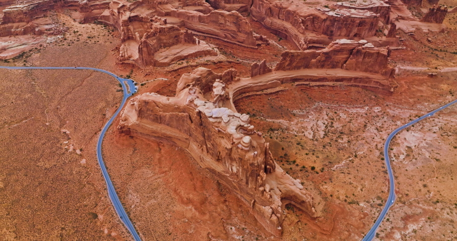 Beautiful canyons of red color with rounded tops and edges. Curved road going around the rocks. Top view.