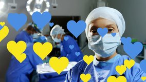 Animation of yellow and blue hearts floating over caucasian female surgeon in face mask. ukraine crisis, health, medicine and international politics concept digitally generated video.