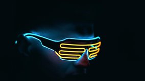 The young man in futuristic glasses in darkness