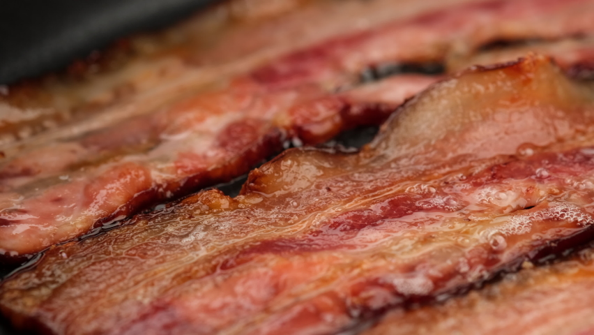 Frying bacon slices in pan, close up. Crispy pieces of delicious Bacon Fried in a Hot Skillet. Traditional breakfast Royalty-Free Stock Footage #1093461697