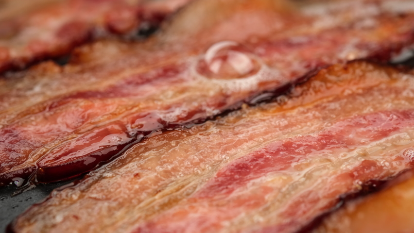 Frying bacon slices in pan, close up. Crispy pieces of delicious Bacon Fried in a Hot Skillet. Traditional breakfast Royalty-Free Stock Footage #1093461697