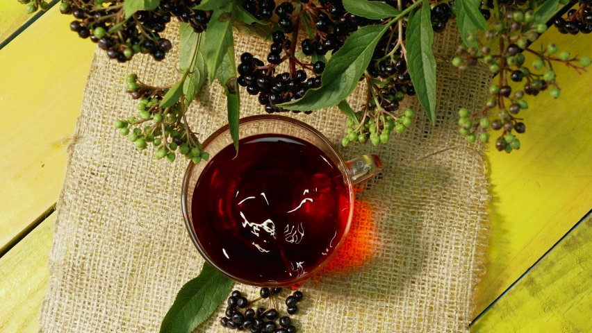 Red tea from fresh black berries in a cup top view on a wooden vintage table. Elderberry tea. Vitamin C with natural tea. Herbal tea for health. Homeopathy. Sambuca berry | Shutterstock HD Video #1093470035