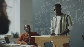 African American male student explaining math formulas on blackboard to group mates and professor during university lesson - Powered by Shutterstock - Get 15% off with code: PIKWIZARD15