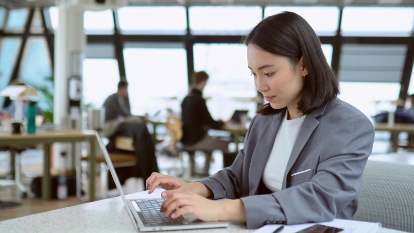 Young adult Asian business woman professional marketing manager using laptop. Female Chinese businesswoman working on computer digital data management sitting at work in big modern corporate office. | Shutterstock HD Video #1093471467