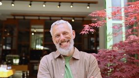 Happy smiling middle aged old grey-haired bearded man laughing outdoors. Cheerful senior adult male entrepreneur, european small business owner close up headshot portrait in slow motion. - Powered by Shutterstock - Get 15% off with code: PIKWIZARD15