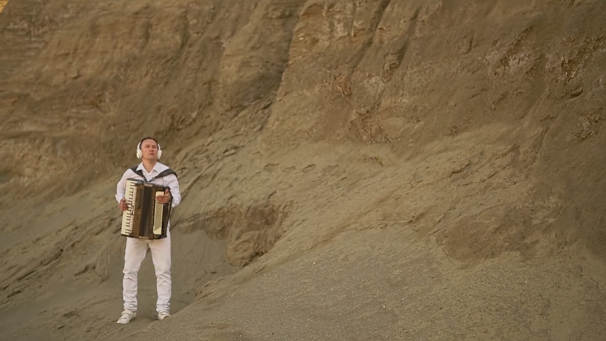 a man in white plays listens to music in headphones and plays it on a musical instrument.general plan