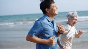 4K Happy Asian senior couple jogging exercise together on the beach in summer morning. Healthy retired man and woman enjoy outdoor lifestyle sport training running workout on beach holiday vacation. - Powered by Shutterstock - Get 15% off with code: PIKWIZARD15