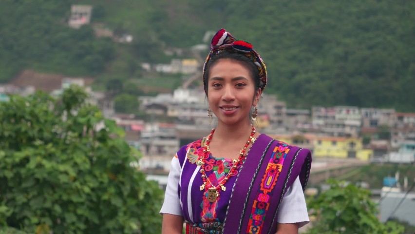 Beautiful Hispanic woman looking at the camera with the mountains and town in the background. Royalty-Free Stock Footage #1093478249