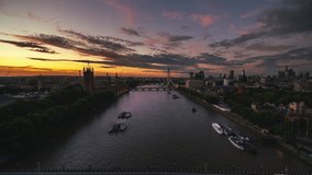 Establishing Aerial View Shot of London UK, United Kingdom, Westminster, very low push along Thames River, marvelous sunset over city