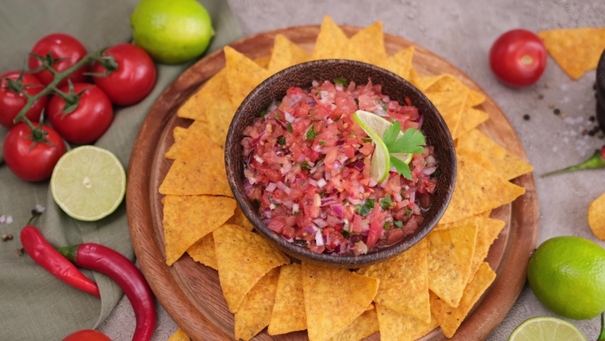 woman puts nacho chip into salsa dip sauce in wooden bowl Royalty-Free Stock Footage #1093482487