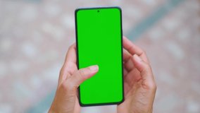 Closeup shot of Indian woman hand using mobile phone with Green screen, Finger swiping up in green screen of the mobile. Green screen mockup template of Mobile phone, Chroma key