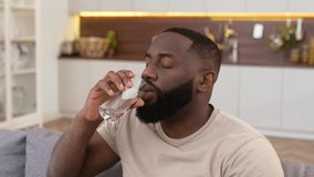 Leading a healthy lifestyle. Close-up of african american man, drinks a glass of clean water with pleasure, care his health, balances fluids in the body, replenishes energy and strength in the body - Powered by Shutterstock - Get 15% off with code: PIKWIZARD15