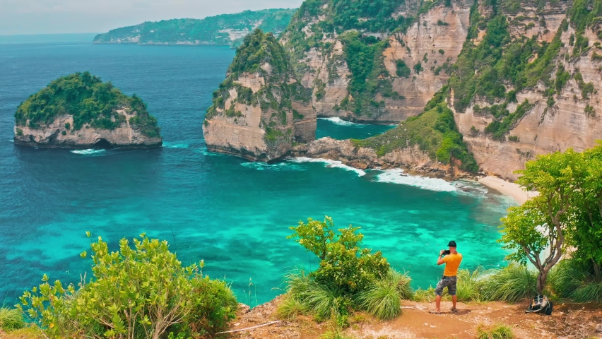 Travel people standing on top mountain cliff at Diamond beach Bali with beautiful mountain cliff in ocean on nature background 4K Aerial view Royalty-Free Stock Footage #1093492779