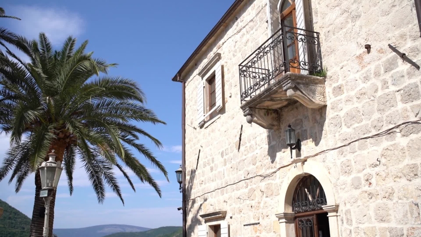 Stone facade of the building with balcony and shutters. Perast, Montenegro