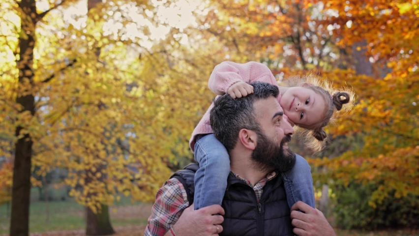 Happy family. Father and daughter walking in autumn park. Little girl sitting on the parent's neck. Cute kid and dad having fun, enjoy spending time together. Happy carefree childhood. Royalty-Free Stock Footage #1093498949