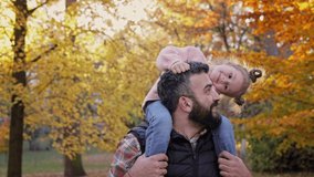 Happy family. Father and daughter walking in autumn park. Little girl sitting on the parent's neck. Cute kid and dad having fun, enjoy spending time together. Happy carefree childhood. - Powered by Shutterstock - Get 15% off with code: PIKWIZARD15