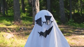black paper and sheet ghost costume for halloween party kid in a costume ghost with eye glasses. Halloween celebration holiday. Funny smiling grimace, slow motion video